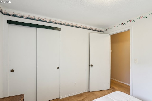 unfurnished bedroom featuring light colored carpet, a closet, and a textured ceiling