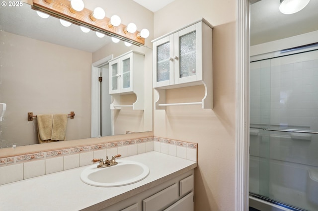 bathroom with an enclosed shower, vanity, and tasteful backsplash