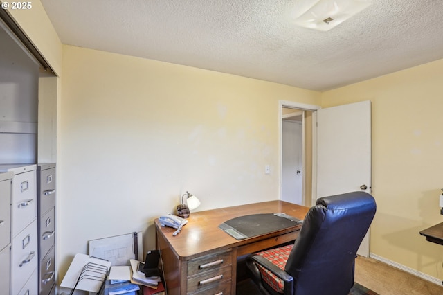 carpeted office space featuring a textured ceiling