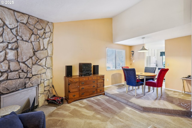 dining space featuring a large fireplace, light carpet, and high vaulted ceiling