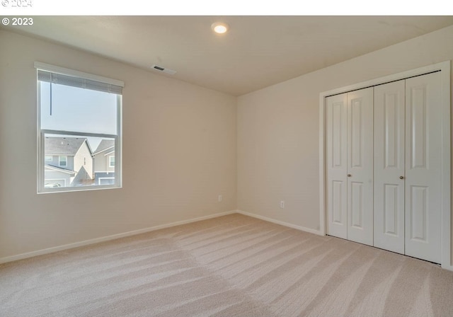 unfurnished bedroom with light carpet and a closet