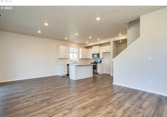 kitchen with stainless steel appliances, a center island, hardwood / wood-style floors, and white cabinets