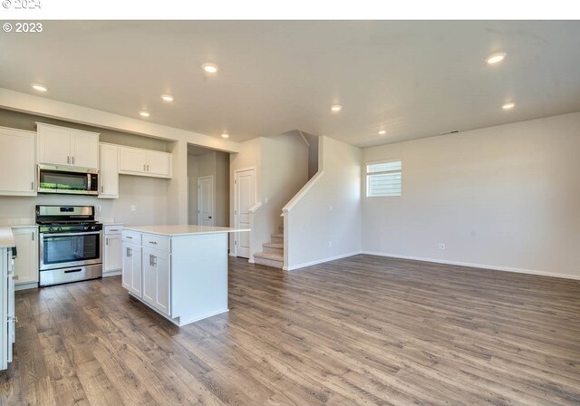 kitchen with stainless steel appliances, a center island, white cabinets, and light hardwood / wood-style floors