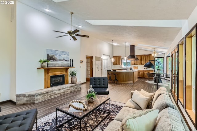 23535 SW Newland Rd, Wilsonville, OR 97070 - living area featuring vaulted ceiling, a brick fireplace, ceiling fan, a skylight, and dark wood-style floors