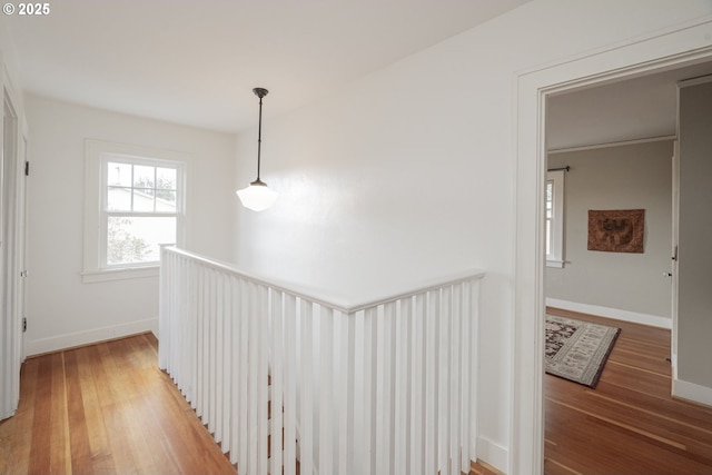 corridor with light wood-type flooring, an upstairs landing, and baseboards