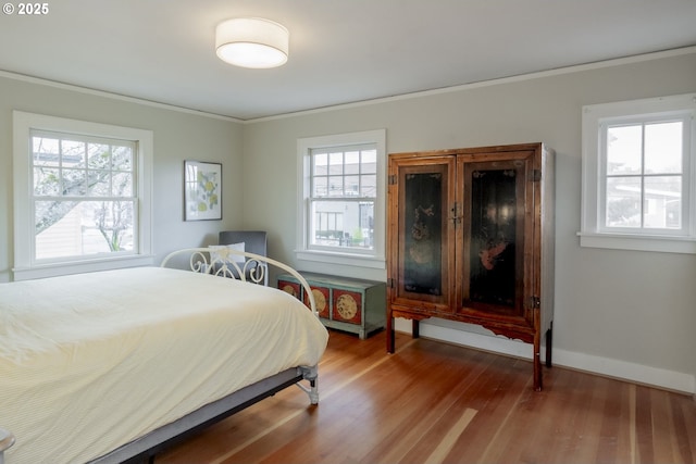 bedroom with baseboards, wood finished floors, and crown molding