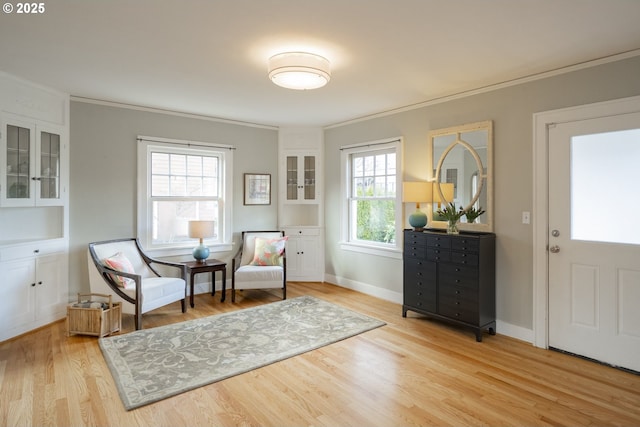 sitting room featuring crown molding, baseboards, and light wood-type flooring