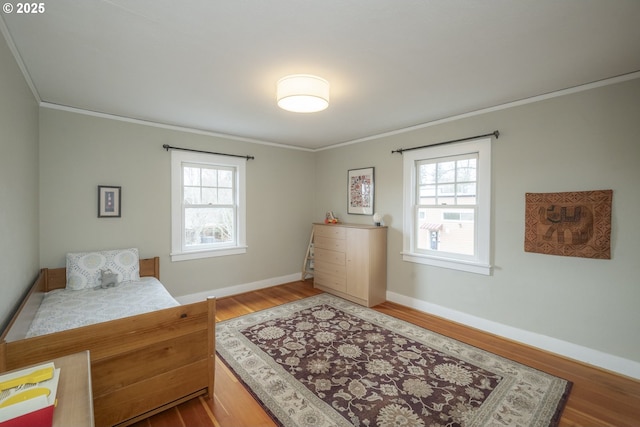 bedroom with baseboards, wood finished floors, and ornamental molding