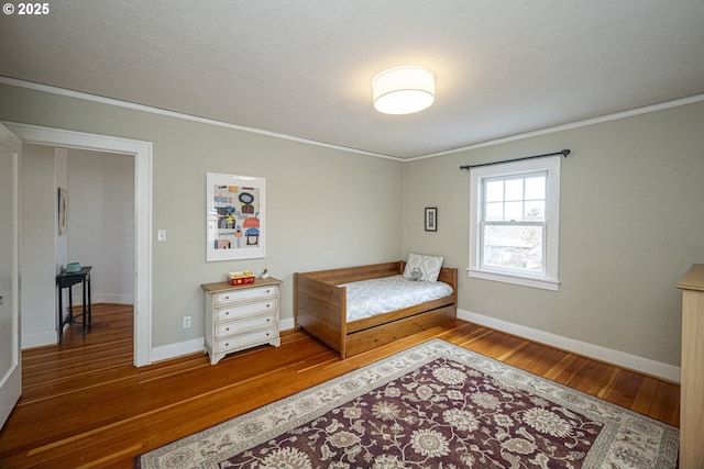 bedroom with hardwood / wood-style flooring, baseboards, and ornamental molding