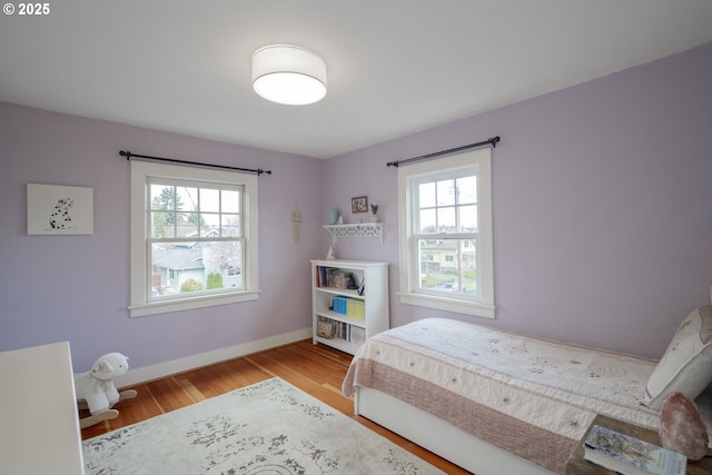 bedroom featuring multiple windows, baseboards, and wood finished floors