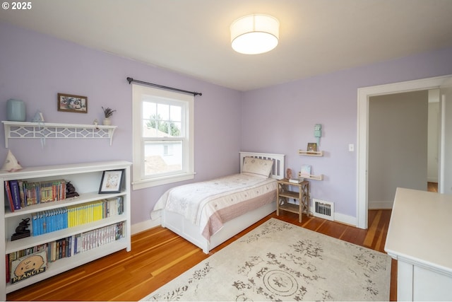 bedroom with visible vents, baseboards, and wood finished floors