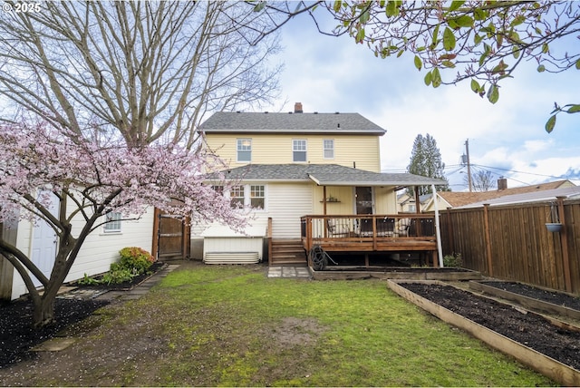 back of house featuring a garden, a yard, a shingled roof, a deck, and fence private yard