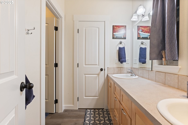 bathroom with vanity, hardwood / wood-style floors, and backsplash