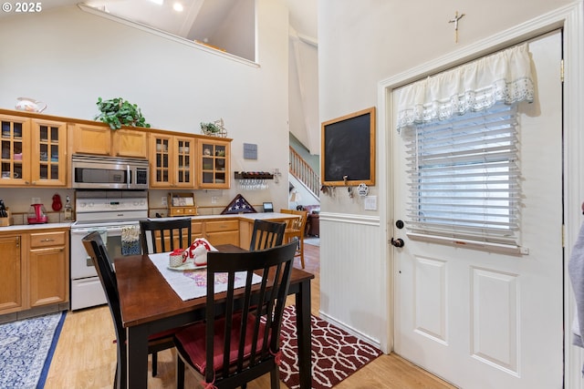 24150 NW Green Mountain Rd, Banks, OR 97106 - dining room with high vaulted ceiling, light wood-style flooring, stairway, and a wainscoted wall