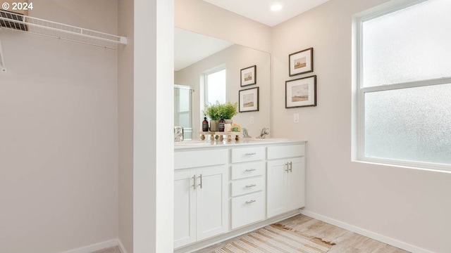 bathroom featuring double vanity, a sink, a shower with shower door, and baseboards