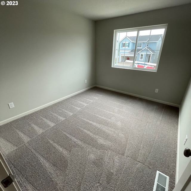 carpeted empty room featuring baseboards and visible vents