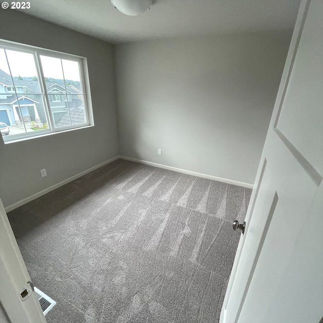 carpeted spare room with baseboards and visible vents