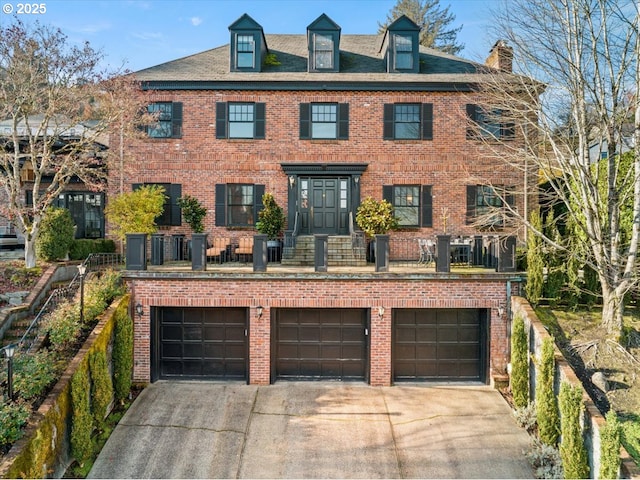 colonial house featuring an attached garage, fence, concrete driveway, and brick siding