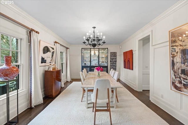 dining area with a chandelier, dark wood-type flooring, a decorative wall, and crown molding