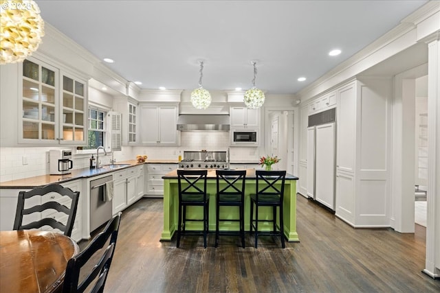 kitchen with built in appliances, a sink, a kitchen breakfast bar, decorative backsplash, and dark wood-style floors