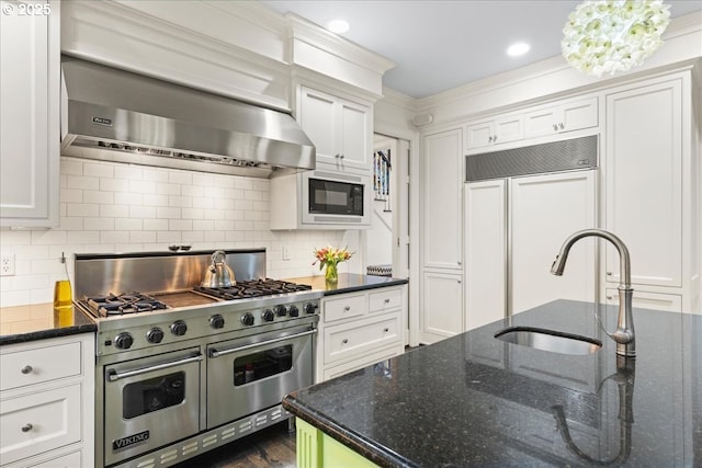 kitchen featuring exhaust hood, white cabinetry, backsplash, and built in appliances