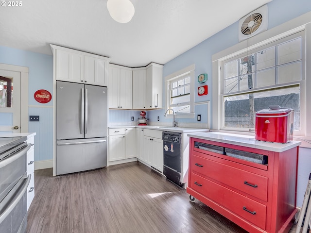 1078 Harrison Ave, Astoria, OR 97103 - kitchen featuring appliances with stainless steel finishes, dark wood-type flooring, light countertops, and white cabinets