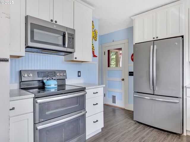 1078 Harrison Ave, Astoria, OR 97103 - kitchen featuring appliances with stainless steel finishes, white cabinetry, light countertops, and light wood-style floors