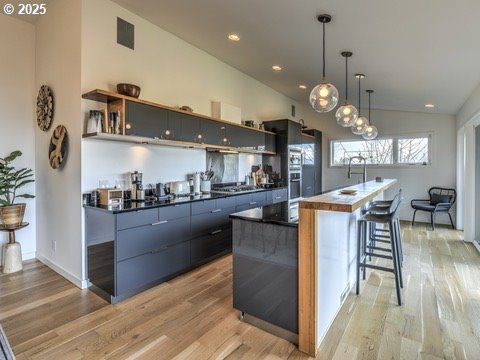 kitchen with a breakfast bar, dark countertops, modern cabinets, and open shelves