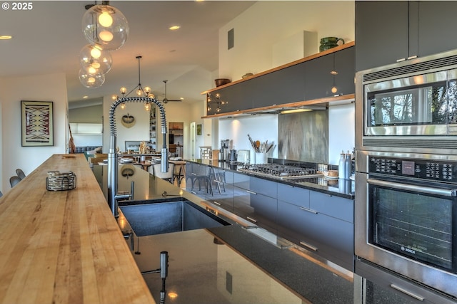 4444 SW Council Crest Dr, Portland, OR 97239 - kitchen with appliances with stainless steel finishes, butcher block counters, vaulted ceiling, a chandelier, and hanging light fixtures