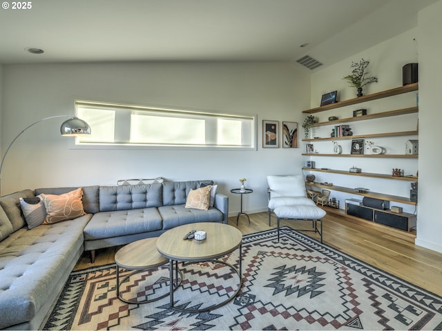 living room with plenty of natural light, visible vents, vaulted ceiling, and wood finished floors