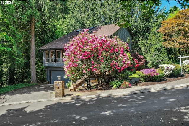 13305 Fox Run, Lake Oswego, OR 97034 - obstructed view of property featuring concrete driveway, an attached garage, stairs, and roof with shingles