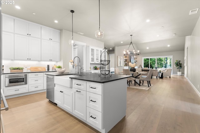 15007 Twin Fir Rd, Lake Oswego, OR 97035 - kitchen featuring stainless steel appliances, dark countertops, light wood-style flooring, a kitchen island with sink, and recessed lighting