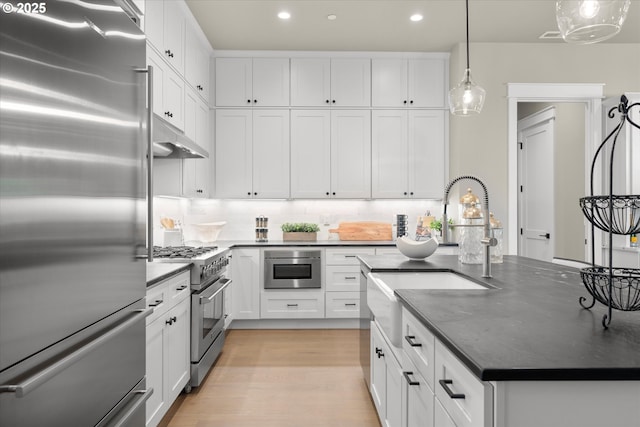 15007 Twin Fir Rd, Lake Oswego, OR 97035 - kitchen featuring high quality appliances, a kitchen island with sink, under cabinet range hood, white cabinetry, and recessed lighting