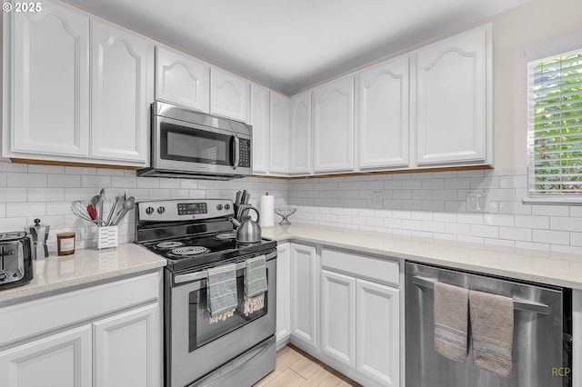 50 Cervantes Cir, Lake Oswego, OR 97035 - kitchen featuring appliances with stainless steel finishes, white cabinets, light stone counters, and decorative backsplash
