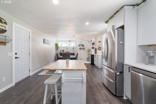3141 SW 176th Ave, Beaverton, OR 97003 - kitchen featuring appliances with stainless steel finishes, butcher block counters, dark wood-style floors, white cabinets, and a kitchen breakfast bar