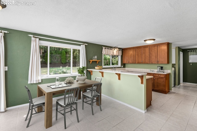3985 Donald St, Eugene, OR 97405 - kitchen with a textured ceiling, brown cabinets, light countertops, a kitchen breakfast bar, and a peninsula