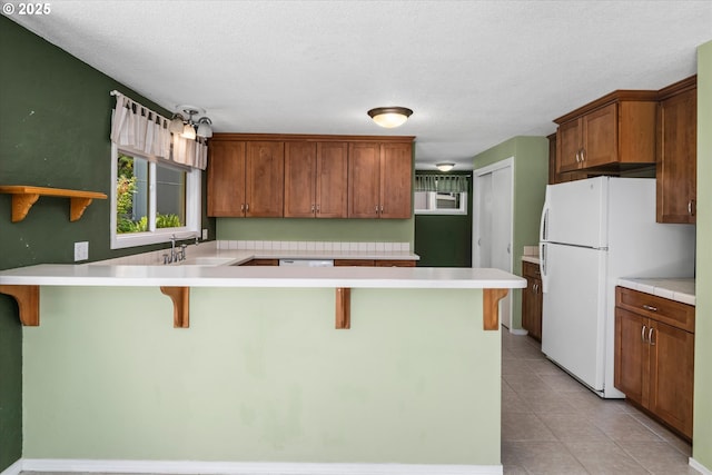3985 Donald St, Eugene, OR 97405 - kitchen with a peninsula, freestanding refrigerator, a sink, a breakfast bar, and light countertops