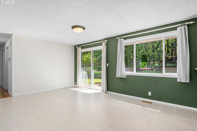 3985 Donald St, Eugene, OR 97405 - tiled empty room featuring plenty of natural light, a textured ceiling, and baseboards