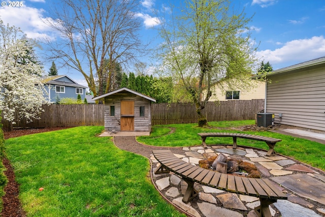 view of yard featuring a fenced backyard, an outdoor structure, an outdoor fire pit, and a shed