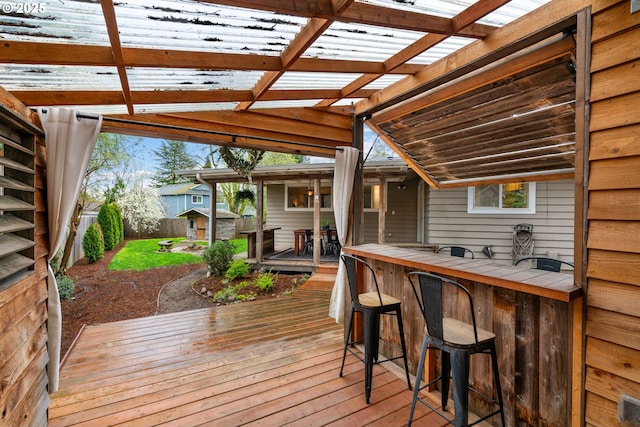 wooden deck featuring a fenced backyard, outdoor dry bar, a pergola, and an outdoor structure