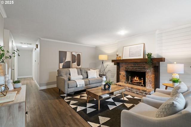 living room featuring crown molding, a fireplace, baseboards, wood finished floors, and visible vents