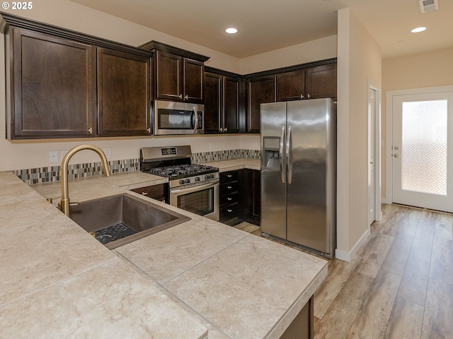 7417 N 92nd Ave, Camas, WA 98607 - kitchen featuring stainless steel appliances, dark brown cabinets, light countertops, light wood-type flooring, and recessed lighting