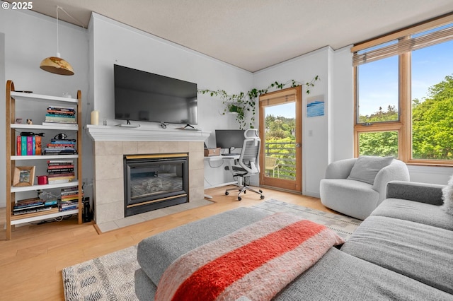 bedroom featuring access to exterior, a tiled fireplace, wood finished floors, and a desk