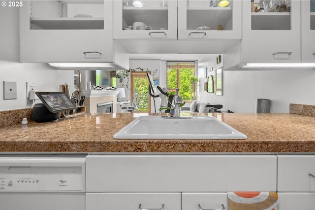 kitchen with white dishwasher, a sink, and white cabinets