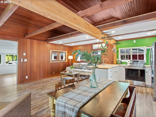 dining room featuring light wood-type flooring, wood walls, wood ceiling, and beamed ceiling