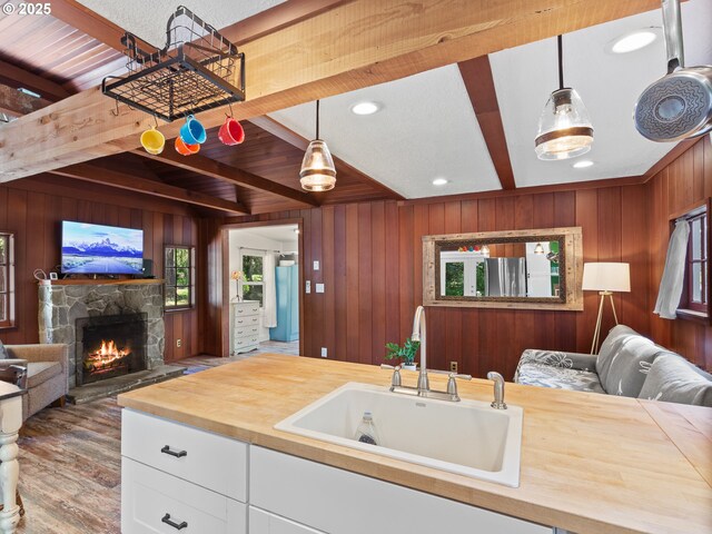 kitchen featuring butcher block countertops, open floor plan, a sink, and beam ceiling