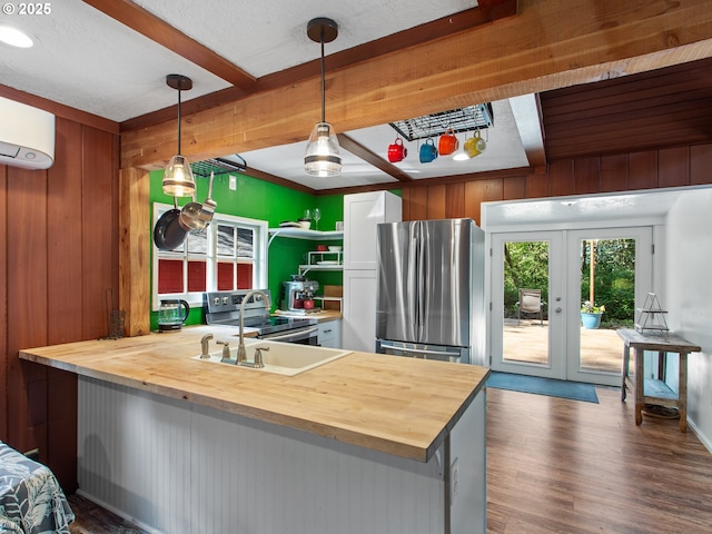 kitchen featuring butcher block countertops, a peninsula, appliances with stainless steel finishes, and beam ceiling