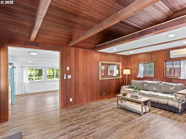 living room with a wall mounted AC, wood finished floors, baseboards, beamed ceiling, and wooden walls