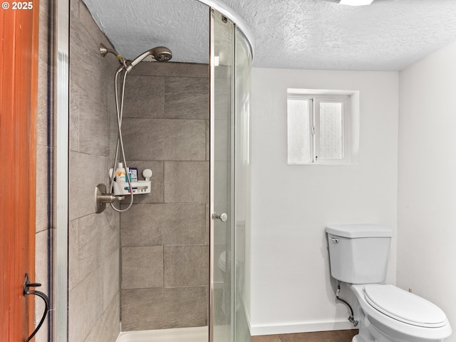full bathroom with a stall shower, toilet, and a textured ceiling