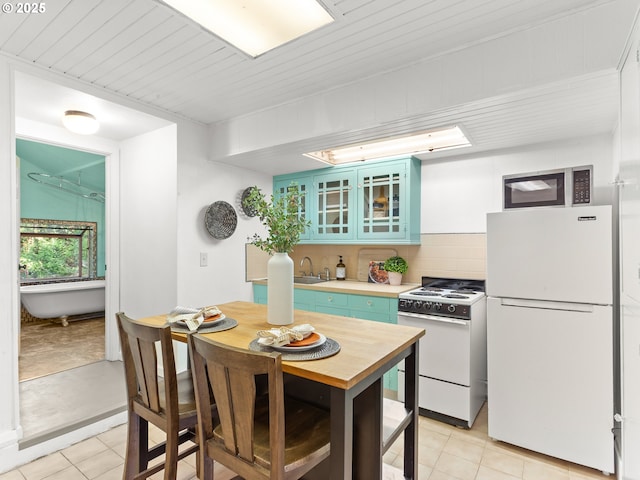 kitchen featuring white appliances, glass insert cabinets, tasteful backsplash, a sink, and light tile patterned floors
